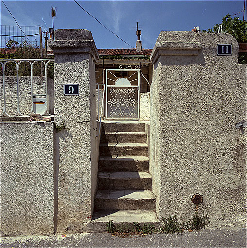 Vue de la clôture, du portail et de l'escalier d'accès au jardin en contre-haut de la voie. ; Vue de la clôture, du portail et de l'escalier d'accès au jardin en contre-haut de la voie.