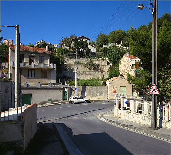 Croisement du boulevard du Belvédère et du chemin du Marinier. Exemple d'étagement des constructions du lotissement Fabre : la parcelle R 88 présente mur de clôture, portail à droite, jardin sur les anciennes restanques et maison au sommet de la pente (121, chemin du Marinier).