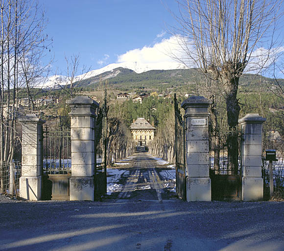 Vue depuis la rue, portail et allée traversant le parc jusqu'à l'élévation sud.