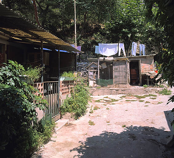 Vue de l'entrée d'un des logis ouest, proche de l'entrée de la courée. Au fond, les cabanes servant d'annexes.