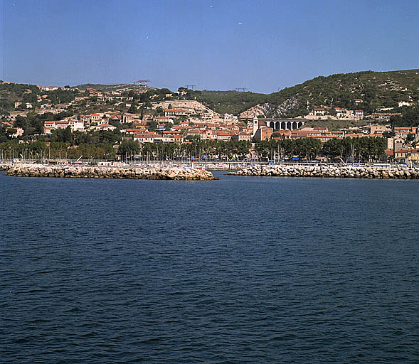 Vue du quartier de l'Eglise depuis la mer. Au premier plan le port de plaisance, la voie dite Plage de l'Estaque bordée de platane. Au centre la butte de l'église, avec à l'arrière-plan, le viaduc de l'Estaque.
