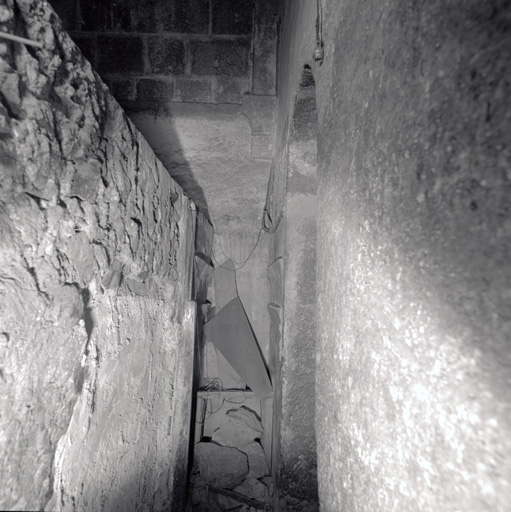 Le clocher. Vue partielle du mur ouest prise de l'escalier situé à l'extrémité du collatéral droit : porte haute (accès au premier étage); cul-de-lampe du cinquième doubleau de ce collatéral, côté gauche.