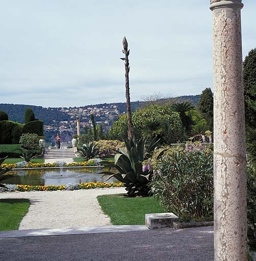 Jardin à la française: vue d'ensemble de l'allée transversale située dans l'axe du bassin, avec une colonne au premier plan, depuis l'est.