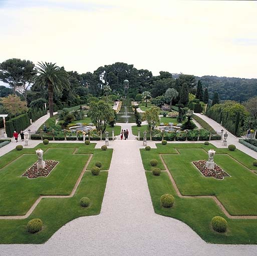 Vue d'ensemble du jardin à la française avec tapis vert au premier plan, depuis la loggia située dans l'axe de la façade sud.