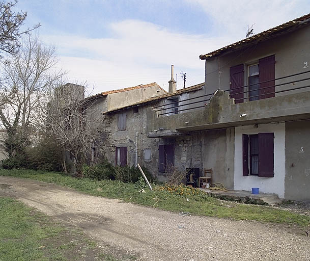 Vue de la façade ouest du logement d'ouvriers mitoyen à d'anciens logements en pierre aujourd'hui désaffectés.