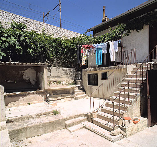 Vue prise dans la cour en terrasse. A droite, escalier et coursière distribuant un logement ; au fond les deux lavoirs.