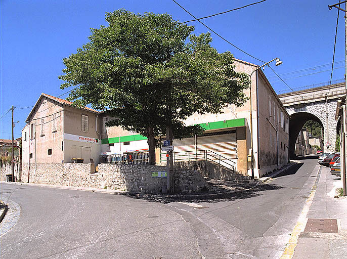 Vue prise du carrefour du chemin de la Nerthe avec la montée Pichou. Au premier plan, immeubles à logements et commerces (parcelles N82, 83, 160), au second plan les viaducs ferroviaires. ; Immeubles à logements et maison et commerce à l'angle du chemin de la Nerthe et de la montée Pichou, (parcelles N82, 83, 160). Ensemble construit vraisemblablement dans les années 1930 par une épicière.