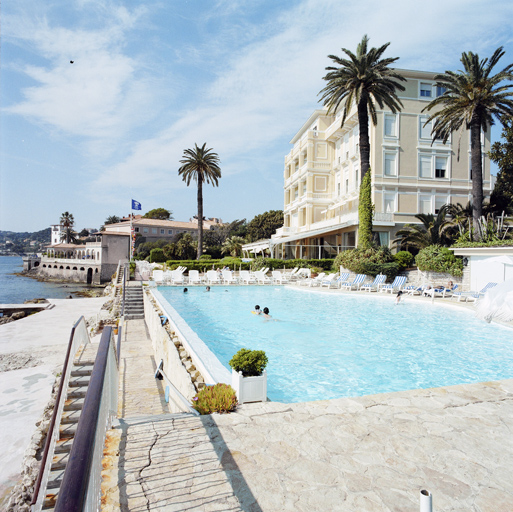 Vue d'ensemble de la piscine depuis le nord avec la façade nord de l'hôtel en arrière plan.