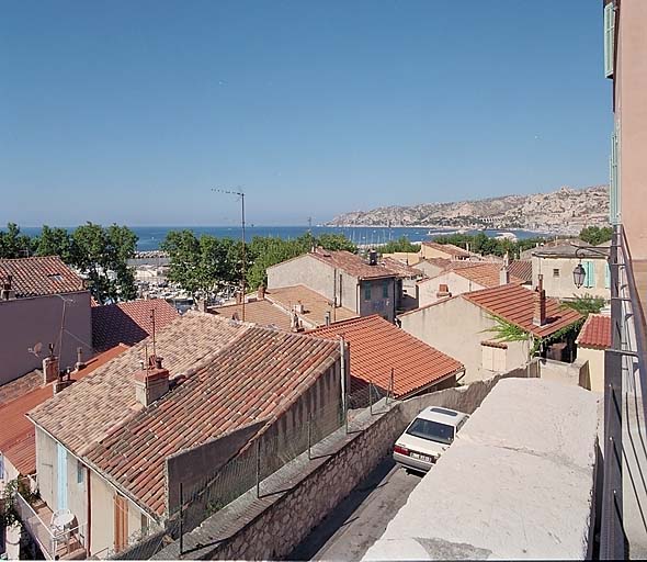 Vue prise depuis la terrasse de la place de l'église (place Malleterre), en direction de Corbières : les toits du hameau, la côte et la mer.