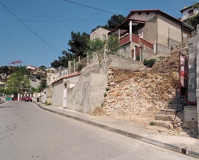 Vue en contre-plongée de la maison du 38 boulevard du Belvédère (parcelle R40) : portail, escalier d'accès, terrasse d'agrément et façade en pignon.
