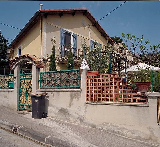 Vue de la clôture et du portail, façade en pignon à l'arrière-plan.