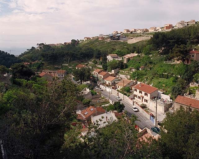 Vue prise depuis le boulevard du Belvédère en direction de l'entrée du vallon, avec la mer à l'horizon et sur la crête le nouveau lotissement des Piches.