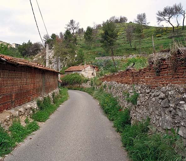 Vue d'un tronçon du chemin des Poudrières, bordé de murs en tuiles plates sur solin de moellons.