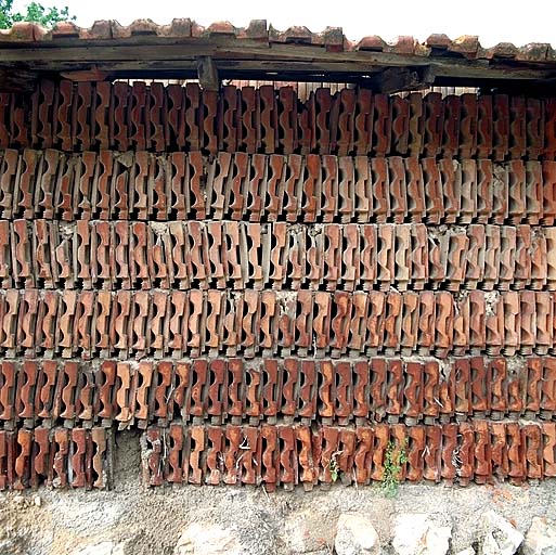 Détail d'un mur de hangar bordant le chemin des Poudrières : solin de moellons surmonté de 6 assises de tuiles plates posées de champs.