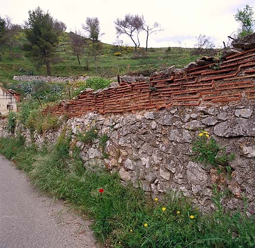 Détail d'un mur bordant le chemin des Poudrières : solin de moellons surmonté d'assises de tuiles plates posées à plat.