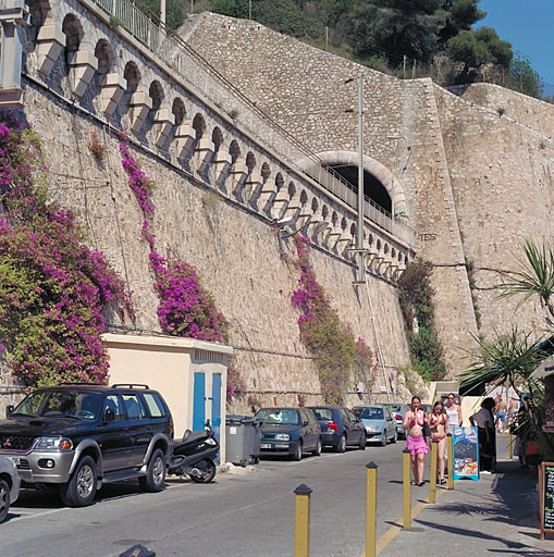 Vue partielle du mur de soutènement de la voie ferrée couronné par de faux mâchicoulis, depuis le sud.