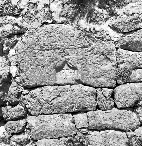 Stèle réemployée dans un mur de soutènement portant l'inscription : "L'an / de la gripe / M 1837 E".