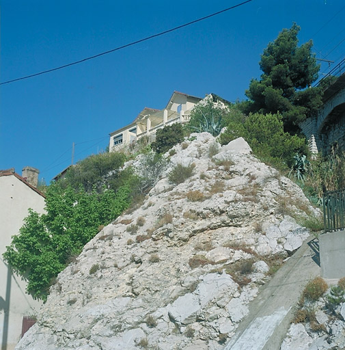 Immeuble à logements, quartier de la Falaise, impasse O52 (parcelles O 53 à O55). Vue de situation, prise en contre-plongée du chemin de la Nerthe. Exemple a-typique constitué de constructions juxtaposés réalisés vers 1926 par un journalier employé chez Chagnaud, et agrandis. Cet ensemble est au plus près de la voie ferrée qui passe à l'arrière du rocher.