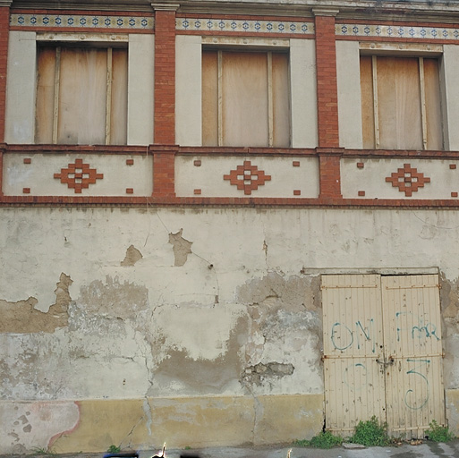 Restaurant : détail de la façade : les 3 travées avec pilastres en briques et bandeau de céramique.