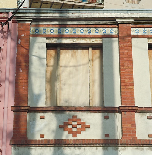 Restaurant : détail d'une travée avec pilastres en brique et bandeau de céramique.