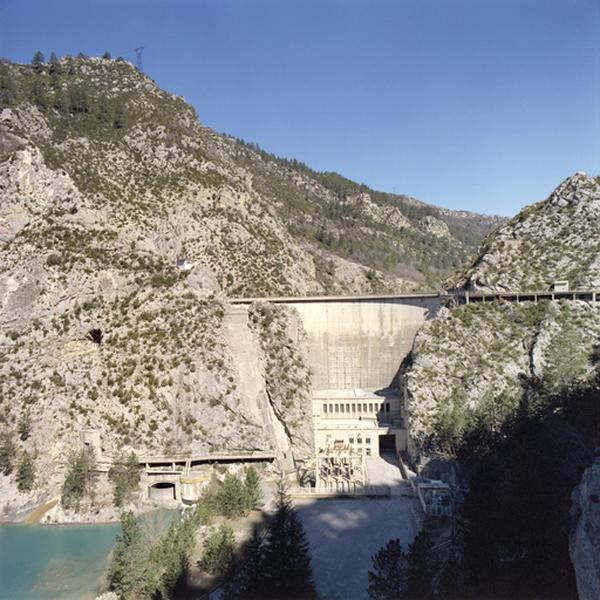 Vue d'ensemble de l'usine et du barrage depuis la route. En bas à gauche, l'extrémité de la galerie de vidange de fond.