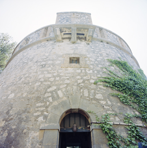 La porte de la tour surmontée d'un jour et d'une bretèche, en contre-plongée.