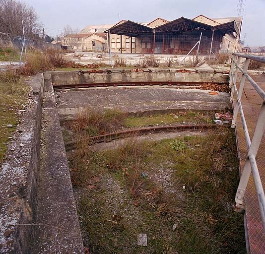 Le pont tournant et sa fosse. Au fond, de droite à gauche, l'atelier de l'outillage et de la précision, la lampisterie puis à l'arrière plan la chaudronnerie de fer. ; Le pont tournant et sa fosse. Au fond, de droite à gauche, l'atelier de l'outillage et de la précision, la lampisterie puis à l'arrière plan la chaudronnerie de fer.