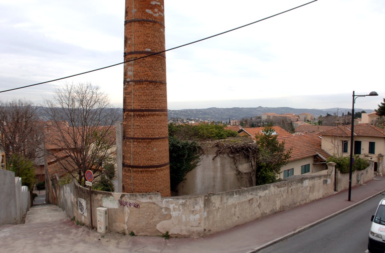 Vue d'ensemble de l'angle nord-ouest de l'usine, avec mur d'enceinte et cheminée.