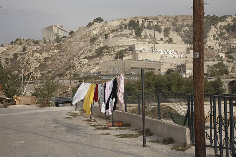 Quartier des Riaux, montée des usines. Etendoirs sur l'esplanade devant la cité ouvrière (Riaux D 157) et paysage de colline avec des vestiges de la cimenterie.