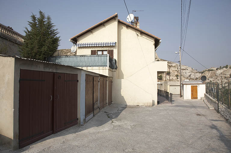 Entrée dans la cité : de gauche à droite : garages, façade latérale en pignon, passage commun, série de remises.