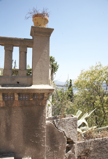 Terrasse devant la bastide : angle de la descente d'escalier, avec pilier carré, corbeaux, frise de céramique et jardinières en ciment en escalier.