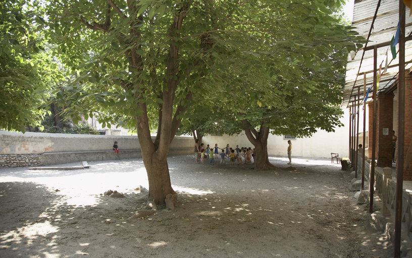 Cour de récréation basse plantée de muriers de Chine, à droite le préau.
