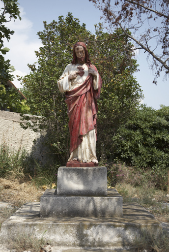Statue du Sacré Coeur sur un socle à emmarchements à l'extrémité sud du terrain.
