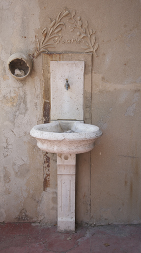Fontaine adossée en marbre, surmontée d'une inscription "Marie" entre des rameaux.