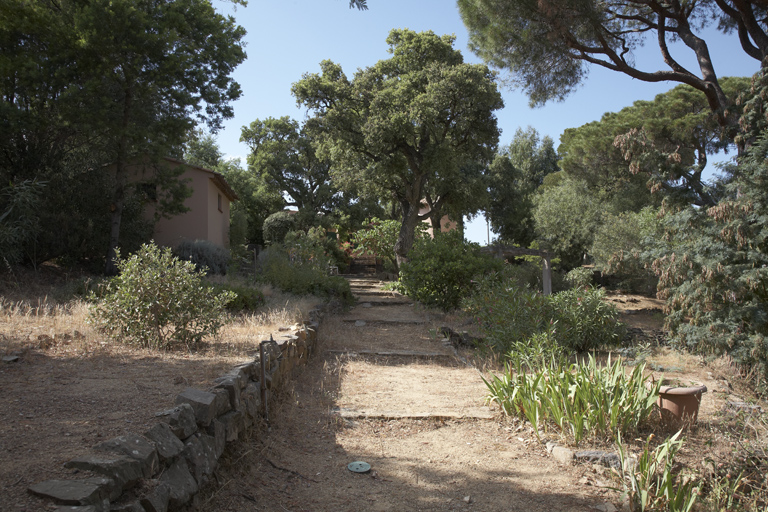 Allée dans le jardin avec la forge à gauche et la maison au fond.