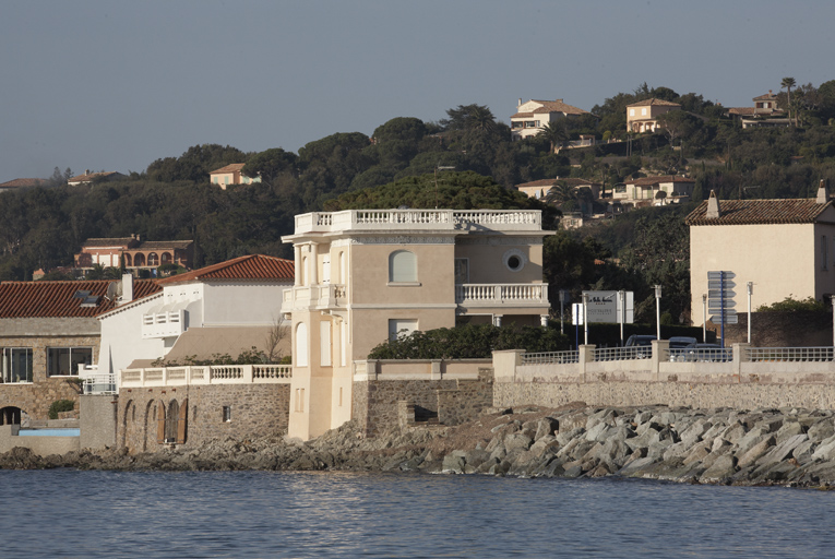 Vue d'ensemble prise de l'est. La maison est accompagnée d'un garage à bateau aménagé dans le mur de soutènement.