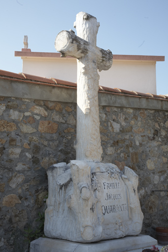 Mur nord-ouest. Concession 62. Tombeau de la famille de Jacques Quaranta. Tombeau surmonté d'une croix en faux bois à laquelle s'enroule du lierre, sur un socle en faux bois orné de chêne et de lierre, sur lequel une pièce de tissu cloué porte l'épitaphe. Fin des années 1920. Marbrier : Pelleti (Saint-Raphaël).