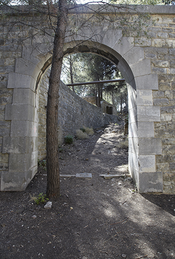 Porte d'accès aux dessus de la lunette réduit (6) , dans son front de gorge, à gauche du magasin à poudres
