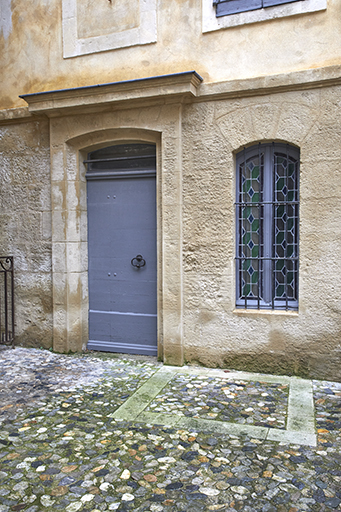 Vue de la porte d'entrée de la maison dite du rabbin Bédarrides et du puits recouvert, jouxtant l'élévation nord de la synagogue.