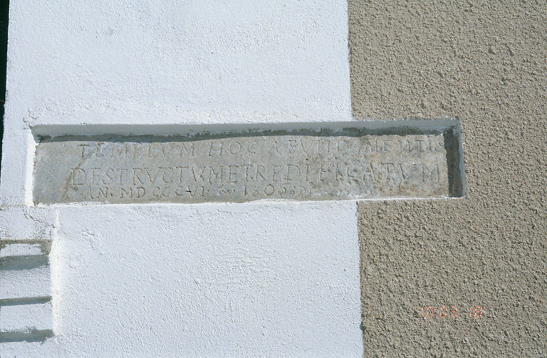 Inscription, en latin, gravée sur une pierre scellée, dans le mur sud : TEMPLUM HOC A FUNDAMENTIS DESTRUCTUM ET REDIFICATUM AN. MDCCCVI. 1806 (cette église a été détruite et reconstruite en 1806).