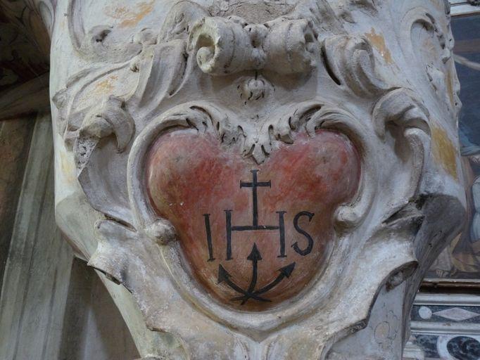 Symbole christique IHS porté sur la rampe d'escalier.