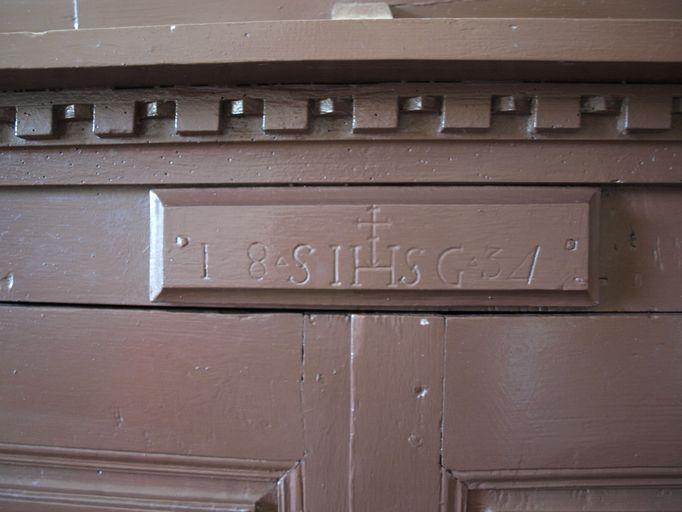 Vue d'ensemble des initiales et de la date portées sur la face antérieure de l'armoire.