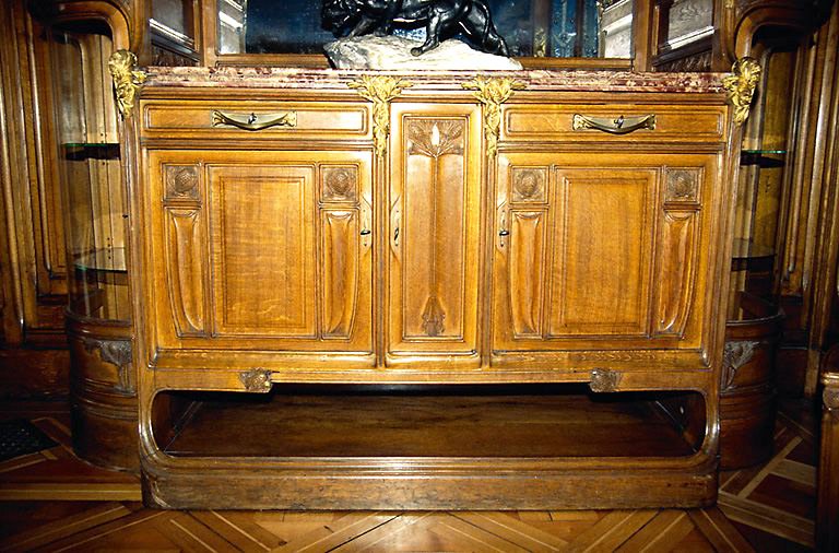 Salle à manger, rez-de-chaussée : meuble en bois sculpté, à motifs de branches et de pommes-de-pin et appliques en bronze ciselé. - (c) Monuments historiques, ADAGP, 1996