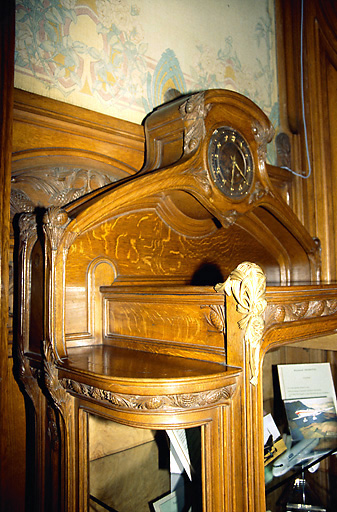 Vestibule : meuble en bois sculpté et horloge sertie, à motifs de branches et de pommes-de-pin, et appliques en bronze ciselé. - (c) Monuments historiques, ADAGP, 1996