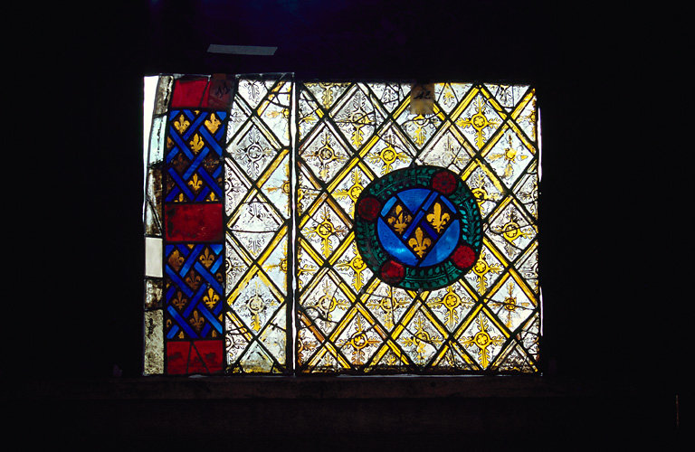 verrière : Panneaux 11, 12 (Ap. R.) bordure alternance de motifs bleus et rouges entre deux filets blancs ; motif de grisaille et de quadrillage dans lequel se trouve des fleurs et des couronnes de feuilles vertes.