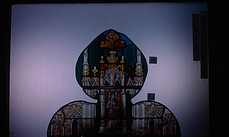 Verrière de la chapelle de Jean Le Roy (baie 44) : Quatre lancettes et tympan à vingt et un ajours (Après restauration) : le haut de la première lancette, dans le pinacle une statuette de la Vierge.