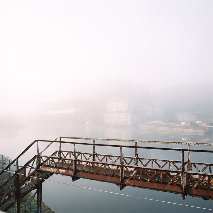 passerelle au-dessus de l'entrée du port du lavoir, en arrière plan la façade sud du lavoir par temps de brouillard. 