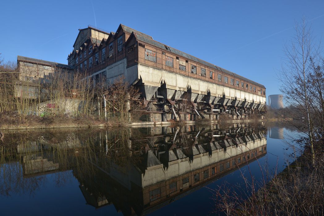 façades sud et ouest du lavoir et son port de chargement. Cheminée de la centrale en arrière plan