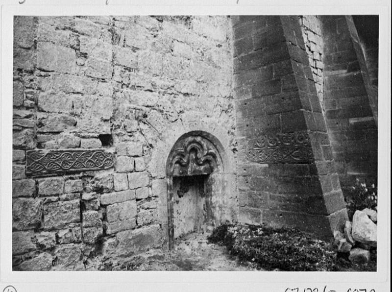 Mur sud de la nef, première travée, vue d'ensemble de la pierre sculptée de palmettes remployée et de la porte murée.