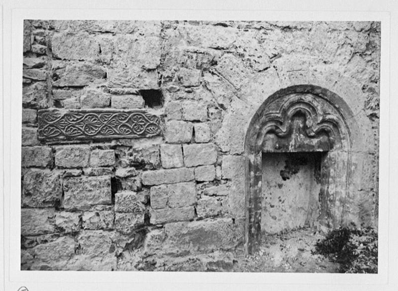 Mur sud de la nef, première travée, vue d'ensemble de la pierre sculptée de palmettes remployée et de la porte murée.